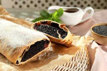 Delicious strudel with poppy seeds and cherries on mat, closeup