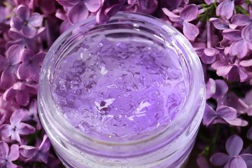 Obraz na płótnie Canvas Jar of cosmetic product and lilac flowers as background, closeup
