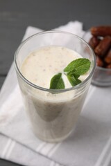 Glass of delicious date smoothie with mint on table, closeup