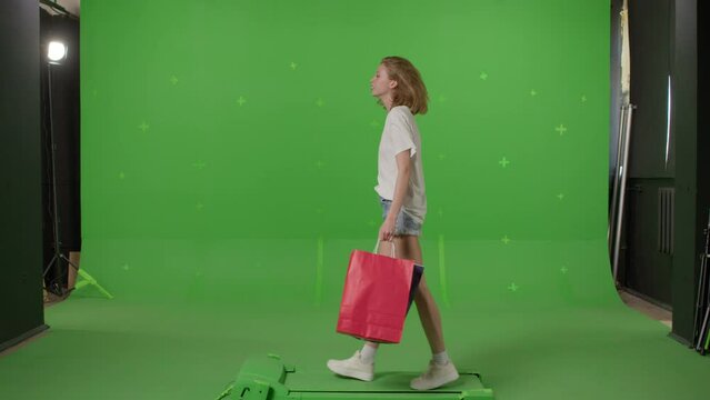 Happy young caucasian woman walking with shopping bags on a Green Screen, Chroma Key background. 4k UHD front side view footage video