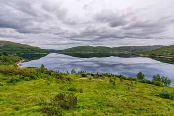 Fototapeta na wymiar Norway Landscape with Lake and Reflection. Cloudy Blue Sky.