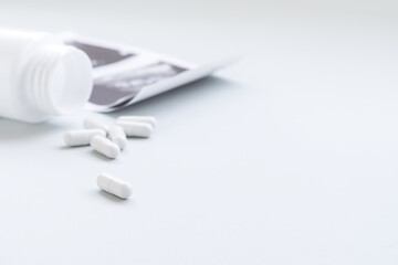 white pill capsules poured out of a white jar and ultrasound examination results on the white table. medicines, treatment and medicine concept