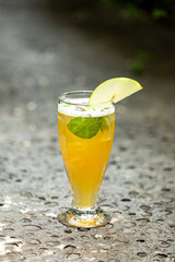 Glass of refreshing iced tea with mint and apple in the garden 
