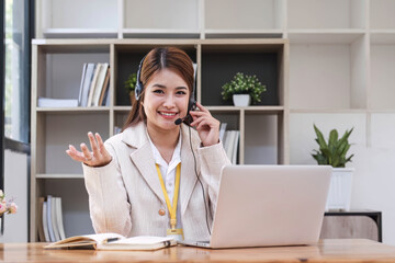 Asian call center with headset and microphone working on her laptop. Female operator provide exceptional customer service. Supportive call center agent helping customer on inquiry. Enthusiastic