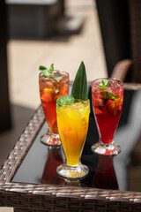 Three glasses of different fruit fresh lemonades on cafe table