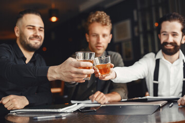 Three bearded men are drinking whiskey and talking.