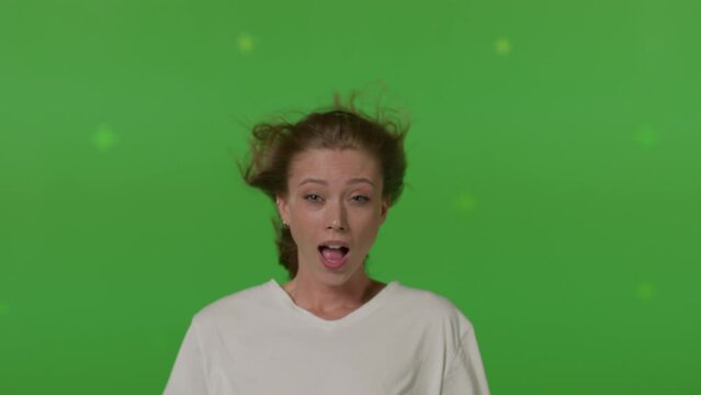 Caucasian girl in front of TV screen getting blown away. Cinema concept with chroma key.