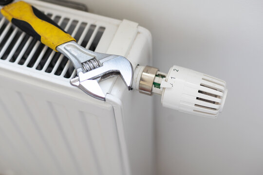 Worker hands repairing radiator with wrench. Close-up.Removing air from the radiator and fixing a heating problem.Dismantling and repair of a heating radiator in a house, apartment.Heating off. 