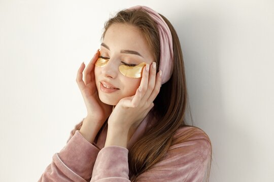 Portrait Of Brunette Woman In Rose Pajamas Applying A Face Patches