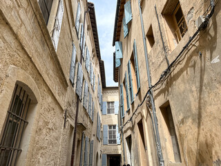 Fototapeta na wymiar Arles, France - 26.04.2023. Street view of Arles, in the south of France. Facade of old residential building with shutters on windows. Charming narrow street view of Arles, Provence south of France.