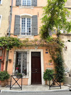 Arles, France - 26.04.2023. Street view of Arles, in the south of France. Facade of old residential building covered ivy or vine plant and with shutters on windows. Street view of Arles, Provence