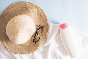 Summer scene with a beach sun hat with glasses and sun cream on a white beach towel. Minimal...