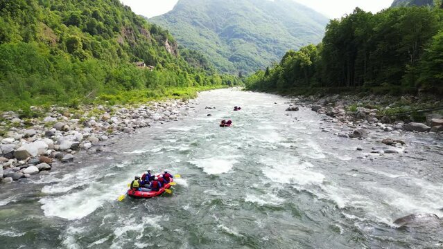 Go rafting on the river with dinghies immersed in the rapids of the stream and the nature of the canyon in Val Sesia Alagna Piedmont Alps mountains - drone view of summer water sport activities 
