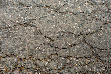 A network of black cracks on the asphalt surface. Road texture with weathered surface, showcasing the effects of time and wear