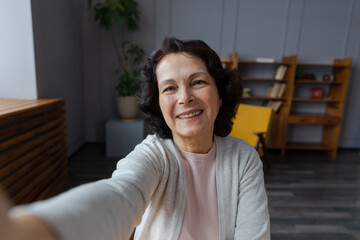 Happy middle aged senior woman talk on video call with friends family. Laughing mature old senior grandmother having fun speaking with grown up children online, Headshot portrait selfie webcamera view