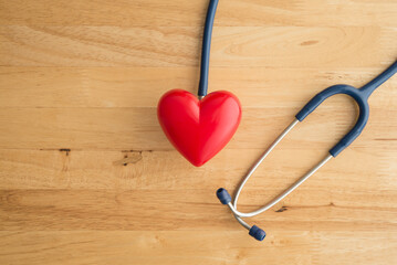 Top view of doctor blue stethoscope and red heart on wooden table background with copy space. Cardiology, world heart health day, heart center in hospital, health medical, life insurance concept.