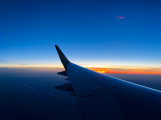 Fototapeta na wymiar Plane wing over beautiful sunset at high altitude in dusk