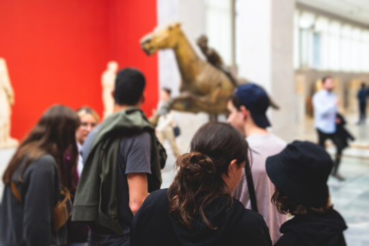 Group of students on excursion tour visit gallery museum with tour guide, a docent with a tourist adult visitors on an archaeology exhibition with contemporary art, hall with paintings and exhibits