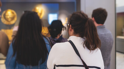 Group of students on excursion tour visit gallery museum with tour guide, a docent with a tourist...