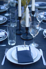 Table setting with white and blue dishes, candles and lavender flowers. Rustic Mediterranean style. Selective focus.