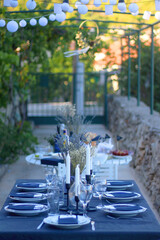 Table setting with white and blue dishes, candles and lavender flowers. Rustic Mediterranean style. Selective focus.