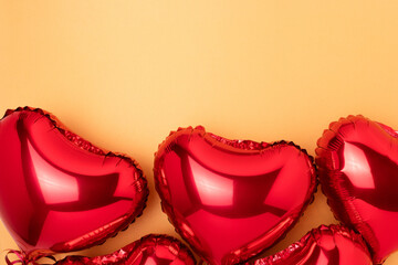 Red inflatable foil balloons in a heart shape. Concept on a gold colored background with place for text.