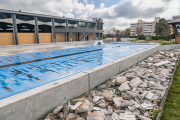 Travaux de rénovation dans une piscine municipale. Réfection du carrelage des plages extérieures autour d'un bassin de natation de 50 mètres