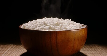 Hot white cooked rice steam bowl black background slow motion, Close up. Sticky rice after cooked. Asian Chinese Thai Japanese Indian nourishment. Restaurant and home cooking 