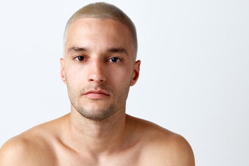 Handsome young shirtless man with clear, spotless skin looking at camera against white studio background. Concept of men's beauty, skincare, cosmetology, spa, health. Copy space for ad
