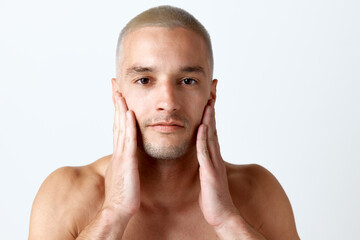Close-up portrait of handsome young man with clear, spotless face taking care after skin against...