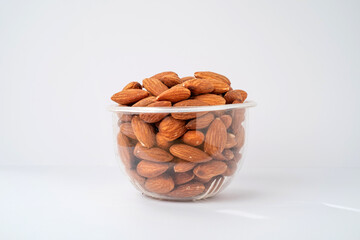 A pile of organic almonds in a glass bowl isolated on white background
