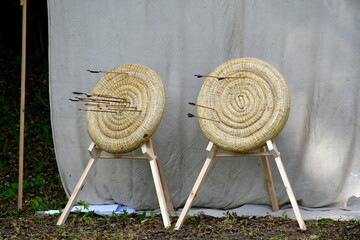A view of a temporary shooting range prepared for an archery and crossbow competition with targets made out of rolled hay on wooden stands with the background being a cloth hanging from two sticks - Powered by Adobe