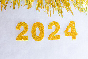 New year 2024 in gold colors and with tinsel on a white background