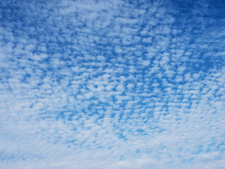 Blue sky with unusual abstract white clouds structure. Strange dramatic clouds pattern texture.