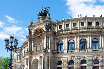 Facade of ancient architectural building with beige walls, statues, decorative elements, semicircular windows and lantern. Historical architecture. Old town. Opera House. Dresden, Germany, May 2023 