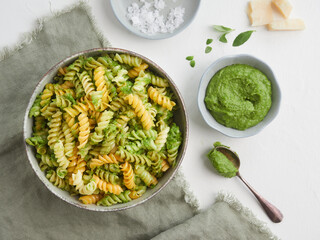 Fussili pasta with pesto sauce. Parmesan cheese and basil herbs at the table. View from above.