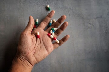 Closeup image of hand and pills on concrete floor with copy space. Overdose, drug addict and...