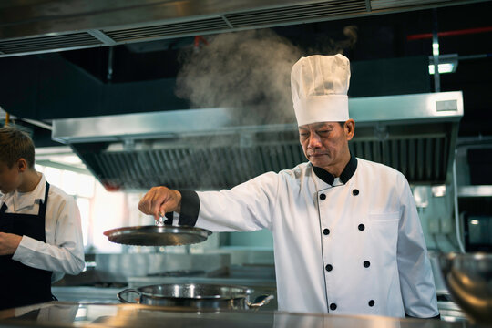 Experienced chef is cooking in a large kitchen in a famous restaurant.