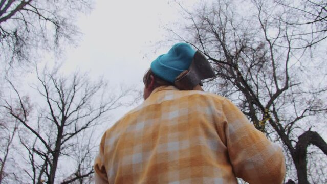 Bearded ginger man with axe looks around in woods