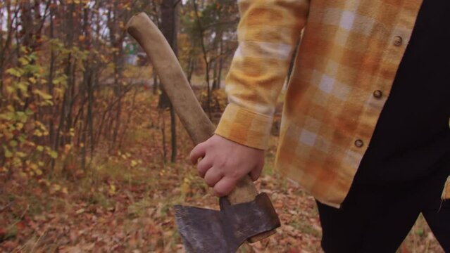 A man walks through autumn forest with axe