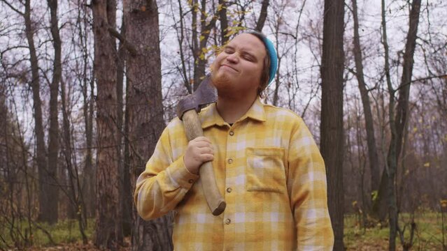 Woodman scratche beard with axe in autumn forest