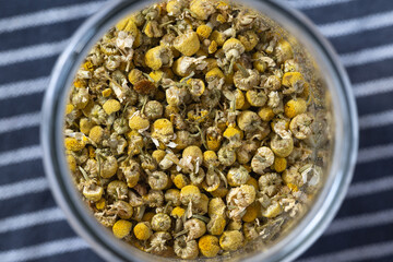 Getrocknete Kamillenblüten im Glas, auf Geschirrtuch