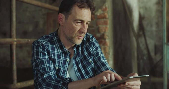 Close Up of a Middle Aged Man Using Digital Tablet to Stay Connected During Work in a Farm. Professional Farmer Making Online Purchases for his Business, Using Technology to do Research
