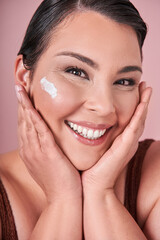 Vertical view of the optimistic female millennial with bare shoulders smiling with moisturizing cream