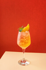 Tequila sunrise cocktail in glass with ice, refreshing summer drink. Cold and refreshing orange punch cocktail with orange slice.  Sunny day shadows.  A refreshing summer cocktail