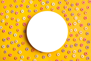 Un círculo en blanco rodeado de froot loops multicolor sobre un fondo anaranjado. Vista superior y...