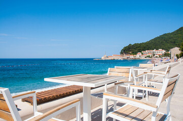 Fototapeta na wymiar Cafe with wooden table and wooden chairs by the sea in Petrovac, Montenegro.