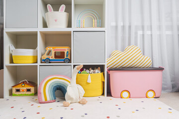White shelving with colorful storage baskets and boxes with toys. Interior design. Organizing and...