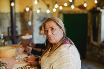Senior latin woman looking on camera during dinner with family