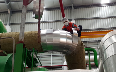 Steam piping insulation installation work by an insulation worker for the steam turbine biomass...